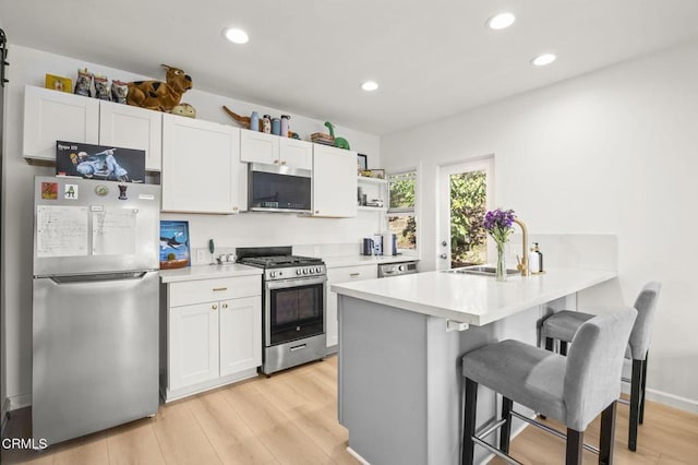 kitchen featuring stainless steel appliances, white cabinetry, sink, and a breakfast bar area