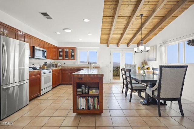 kitchen featuring light tile patterned flooring, hanging light fixtures, stainless steel appliances, wooden ceiling, and an inviting chandelier