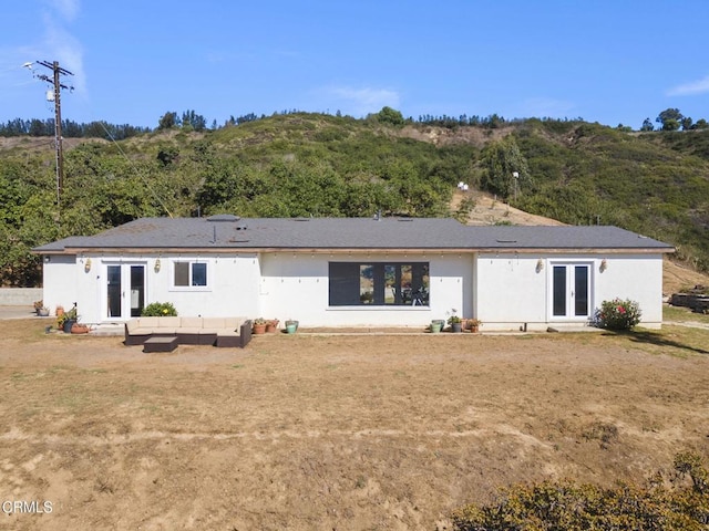 rear view of house with a lawn, outdoor lounge area, and french doors