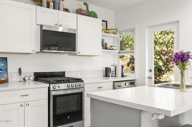 kitchen with light countertops, appliances with stainless steel finishes, open shelves, and white cabinets