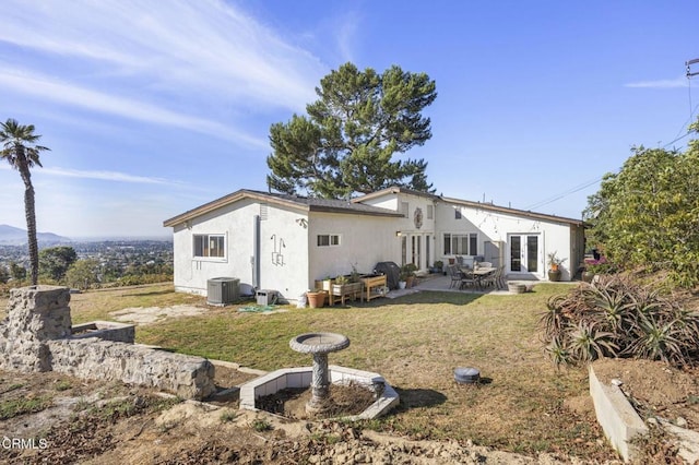 rear view of house featuring a patio, cooling unit, a yard, french doors, and stucco siding