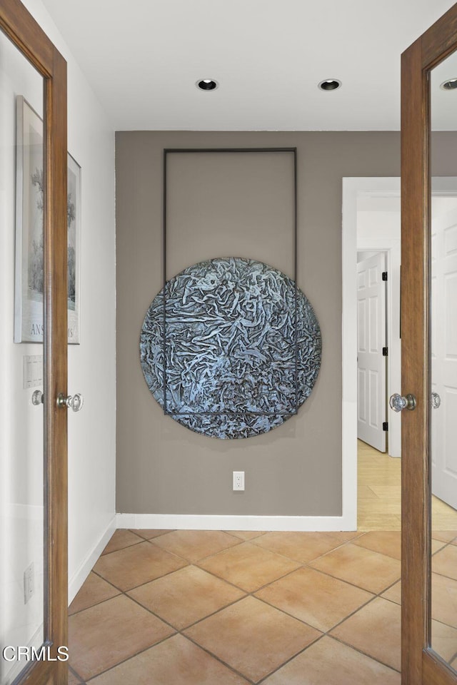 hallway with light tile patterned floors and baseboards