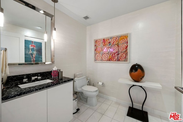 bathroom with toilet, vanity, and tile patterned floors