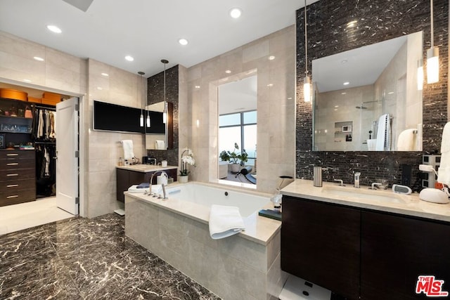 bathroom with plus walk in shower, tile walls, and vanity