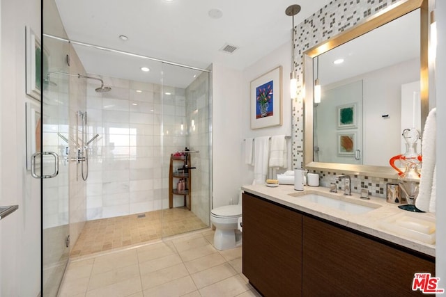 bathroom featuring toilet, a shower with shower door, backsplash, tile patterned floors, and vanity