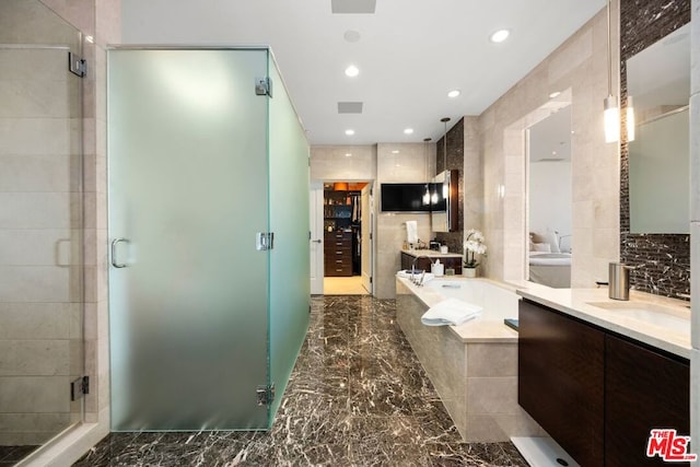 bathroom featuring tile walls, vanity, and shower with separate bathtub