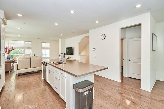 kitchen featuring white cabinetry, a center island with sink, dishwasher, light hardwood / wood-style flooring, and sink