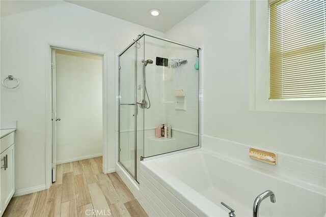 bathroom featuring vanity, plus walk in shower, and hardwood / wood-style floors