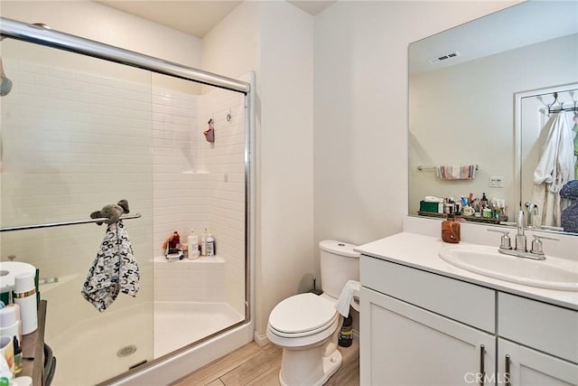 bathroom with vanity, hardwood / wood-style floors, a shower with door, and toilet