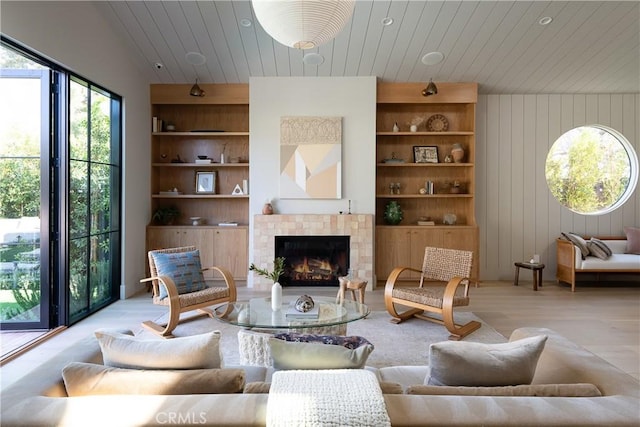 living room with wood ceiling, wood walls, lofted ceiling, a tile fireplace, and built in shelves