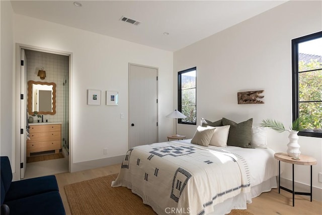 bedroom with light wood-type flooring and ensuite bath