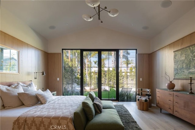 bedroom featuring vaulted ceiling, a chandelier, light hardwood / wood-style flooring, and wooden walls