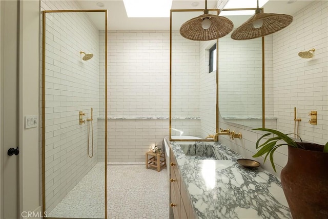 bathroom with a shower with shower door, vanity, and a skylight