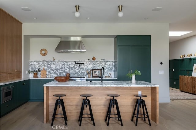 kitchen featuring light stone countertops, a kitchen breakfast bar, wall chimney exhaust hood, and a kitchen island