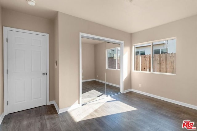 unfurnished bedroom with a closet and dark wood-type flooring