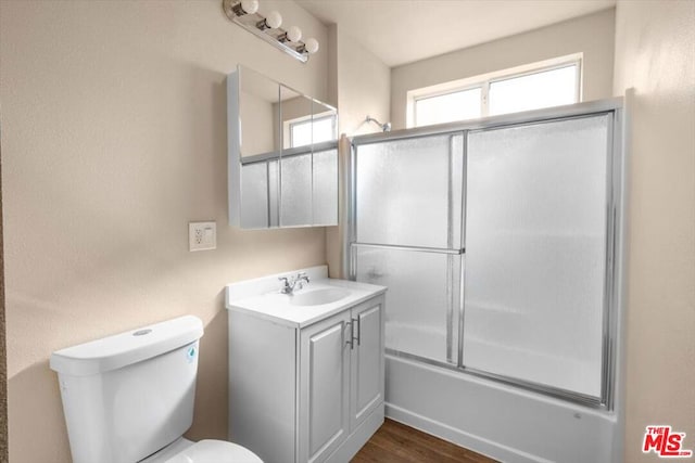 full bathroom featuring toilet, bath / shower combo with glass door, hardwood / wood-style floors, and vanity