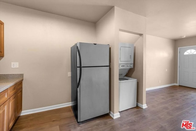 laundry room with stacked washer / dryer and dark hardwood / wood-style flooring