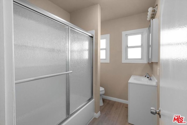 full bathroom with toilet, enclosed tub / shower combo, hardwood / wood-style flooring, and vanity