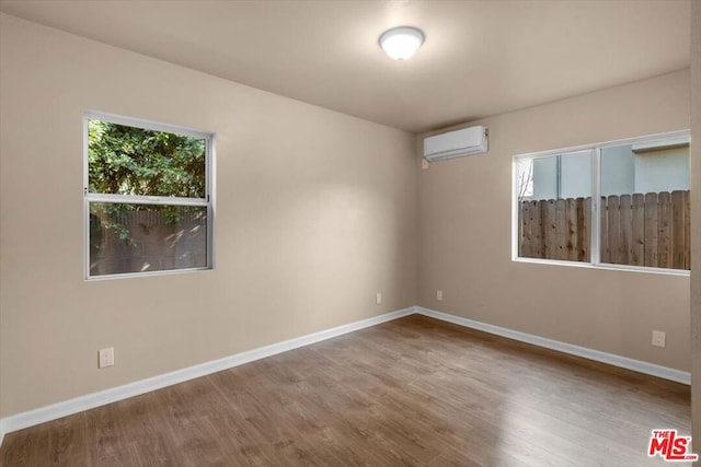 unfurnished room featuring an AC wall unit and hardwood / wood-style flooring