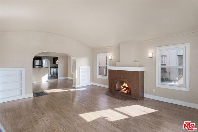 unfurnished living room featuring brick ceiling, vaulted ceiling, and dark wood-type flooring