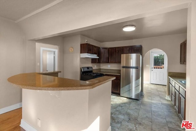 kitchen featuring range, sink, stainless steel refrigerator, a breakfast bar, and dark brown cabinets