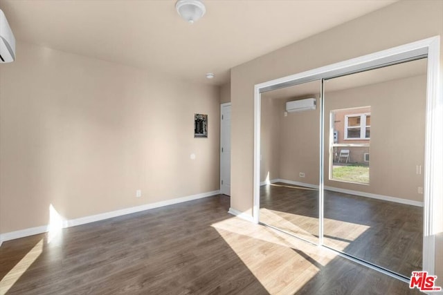 empty room featuring dark hardwood / wood-style floors and a wall mounted air conditioner