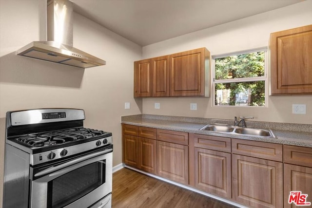 kitchen with gas range, sink, dark hardwood / wood-style floors, and wall chimney exhaust hood