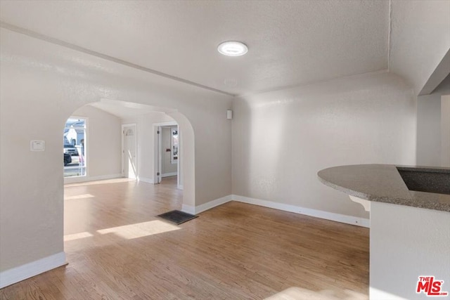 unfurnished dining area featuring wood-type flooring and a textured ceiling