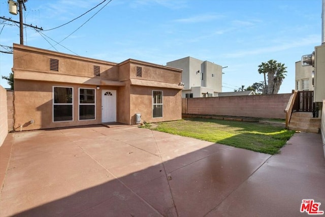 rear view of property with a lawn and a patio