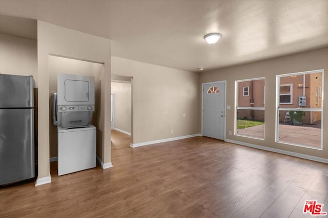 unfurnished living room with stacked washer / dryer and wood-type flooring