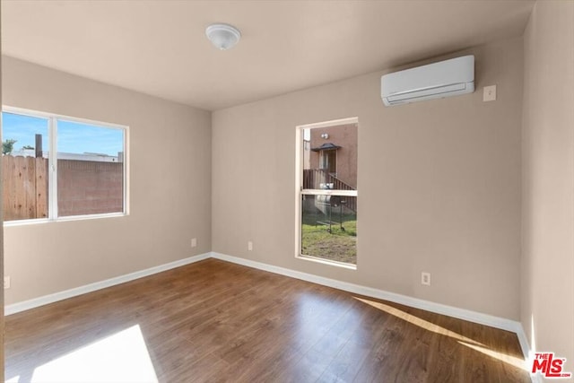 empty room with an AC wall unit and hardwood / wood-style flooring