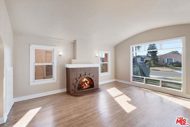 living room with a wealth of natural light, wood-type flooring, and lofted ceiling