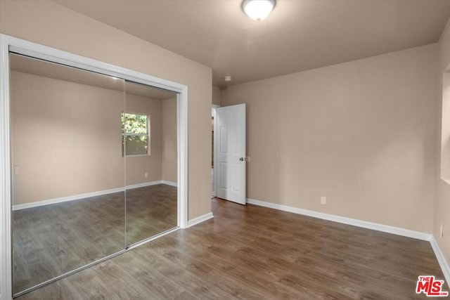 unfurnished bedroom with a closet and dark wood-type flooring