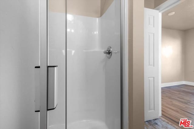 bathroom with an enclosed shower and hardwood / wood-style floors