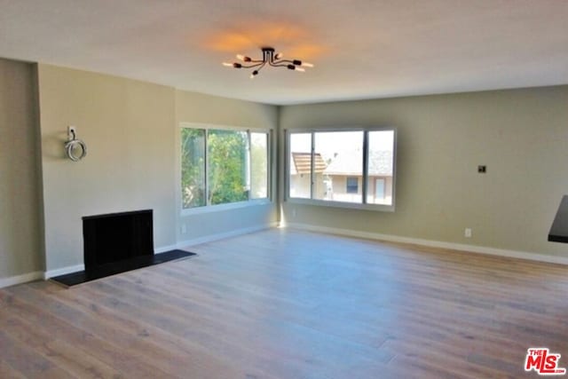 unfurnished living room with a chandelier and hardwood / wood-style flooring