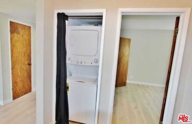 clothes washing area with light wood-type flooring and stacked washer / drying machine