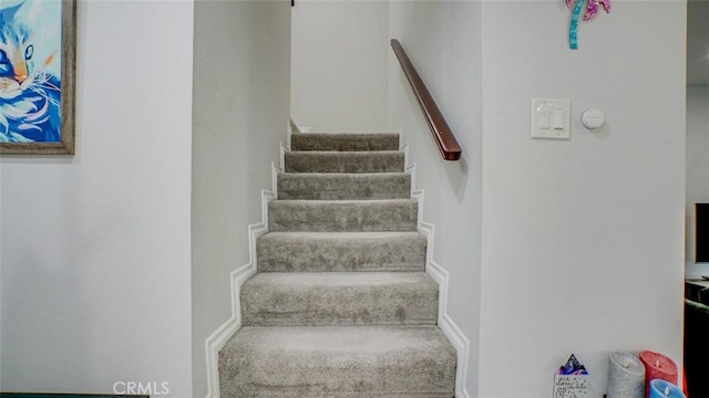 staircase featuring carpet floors and baseboards