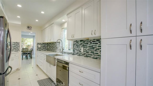 kitchen featuring tasteful backsplash, black dishwasher, sink, white cabinets, and stainless steel refrigerator with ice dispenser