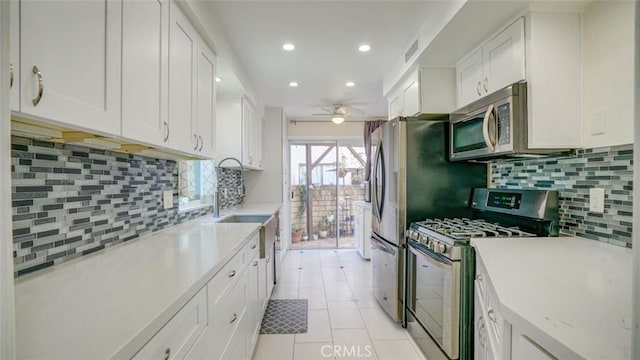 kitchen featuring white cabinets, decorative backsplash, light tile patterned floors, ceiling fan, and stainless steel appliances