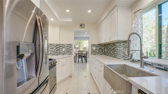 kitchen with stainless steel refrigerator with ice dispenser, white cabinetry, sink, and black gas range