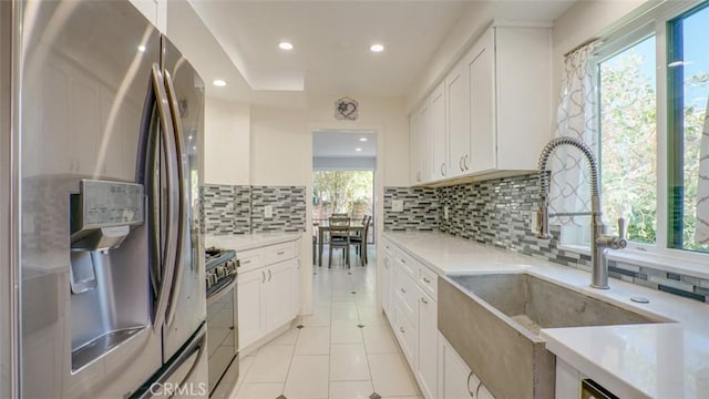 kitchen featuring stainless steel fridge, range with gas stovetop, a sink, and light countertops