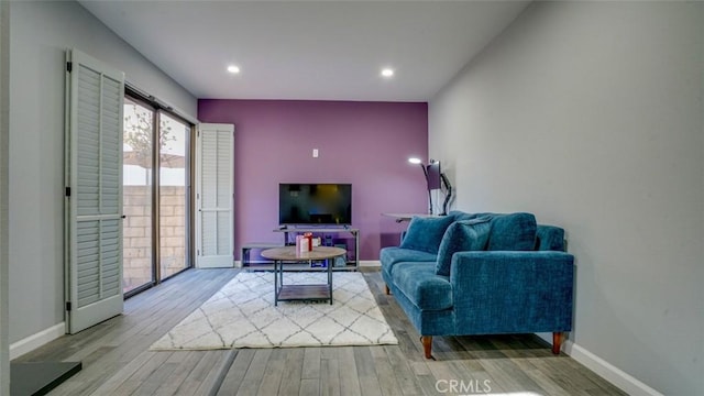 living area featuring baseboards, wood finished floors, and recessed lighting