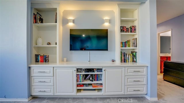 bar with white cabinetry, light colored carpet, and built in features