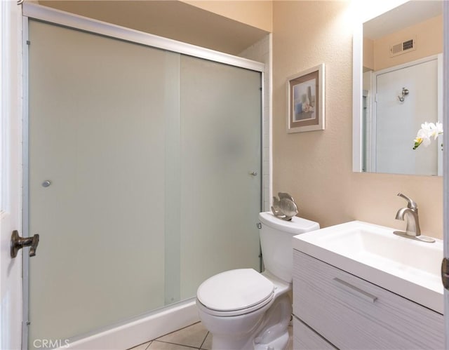 bathroom with tile patterned flooring, vanity, a shower with shower door, and toilet