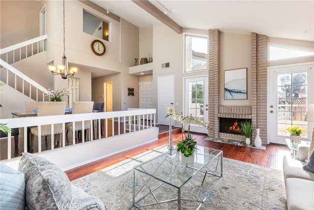 living room with an inviting chandelier, dark hardwood / wood-style floors, a fireplace, and high vaulted ceiling