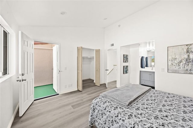 bedroom featuring connected bathroom, lofted ceiling, and light wood-type flooring