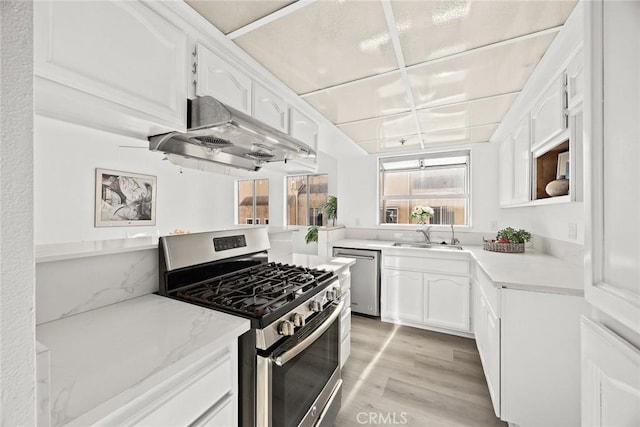 kitchen with sink, light wood-type flooring, appliances with stainless steel finishes, white cabinets, and ventilation hood