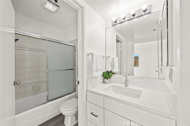 full bathroom with toilet, enclosed tub / shower combo, hardwood / wood-style floors, and vanity