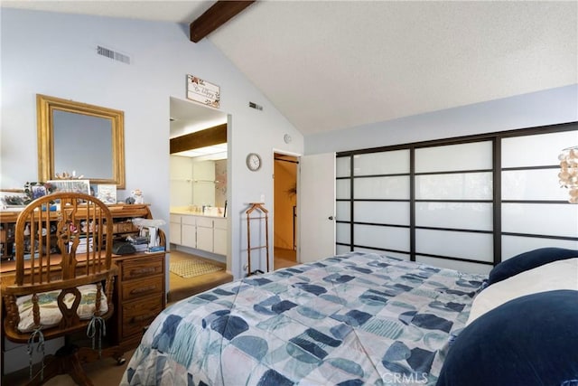 bedroom with ensuite bathroom and lofted ceiling with beams