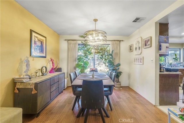 dining room featuring a healthy amount of sunlight, light hardwood / wood-style floors, and a notable chandelier